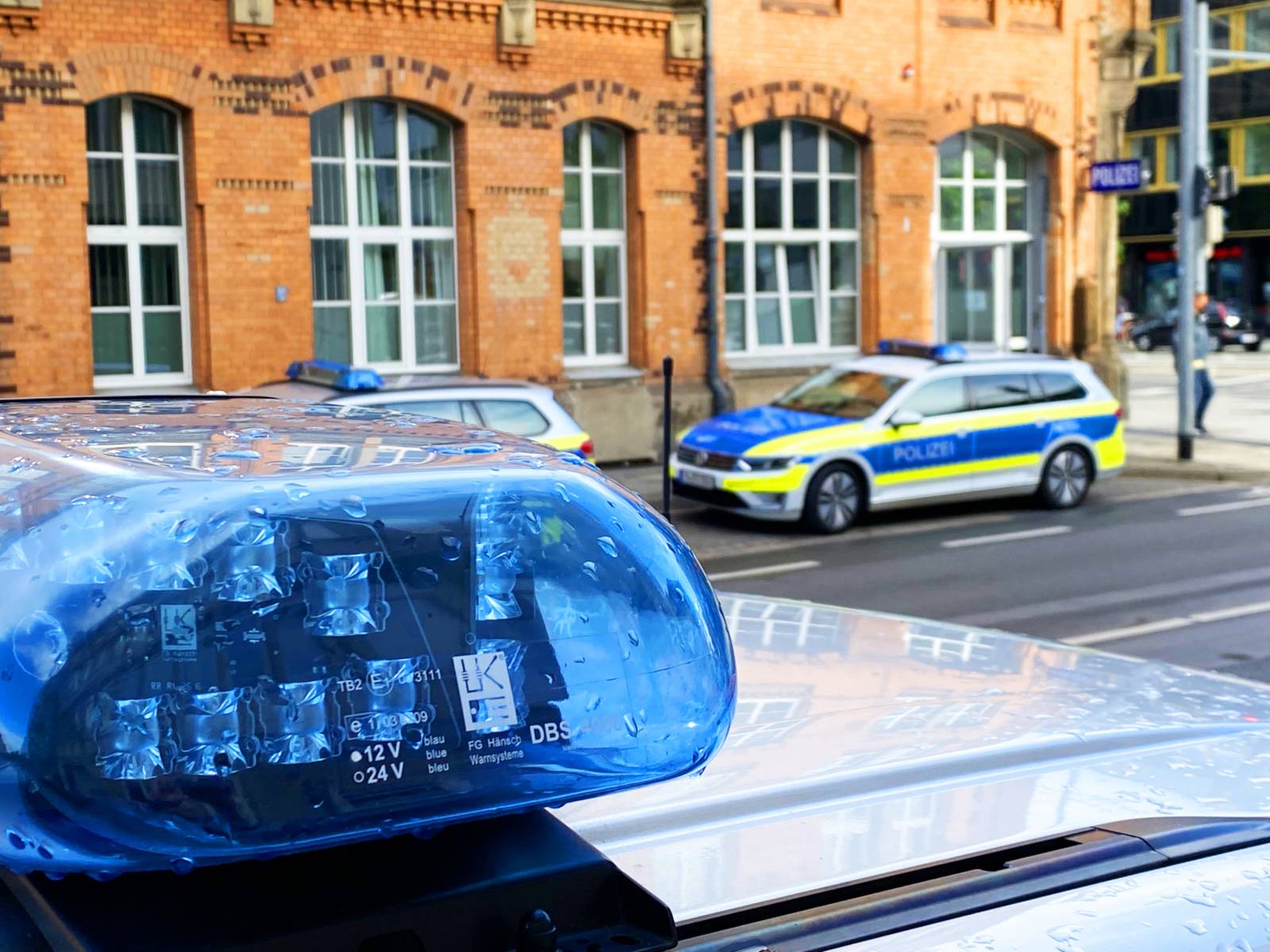 Polizeifahrzeuge stehen vor dem Dienstgebäude in der hannoverschen Herschelstraße, im Vordergrund Blaulicht auf einem Polizeifahrzeug